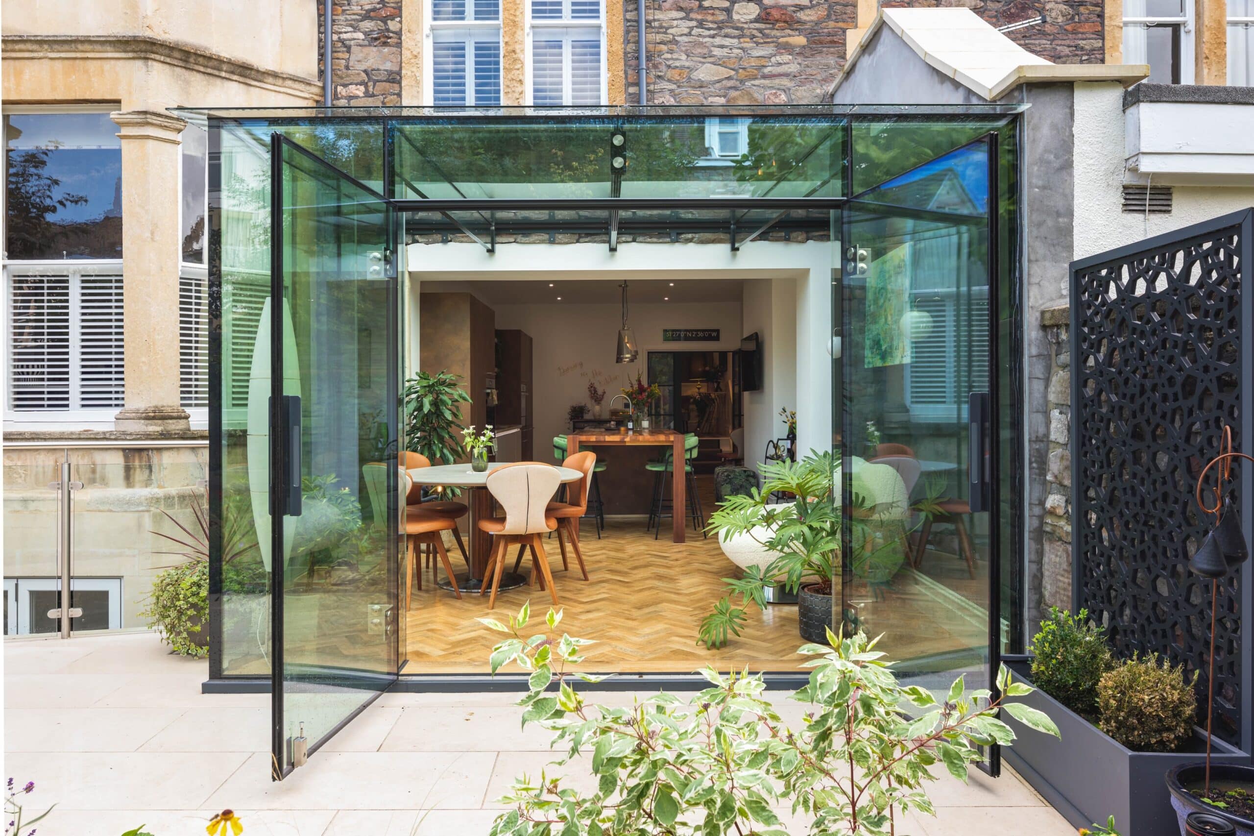 Open-plan kitchen extension with glass doors connecting to a landscaped garden 3