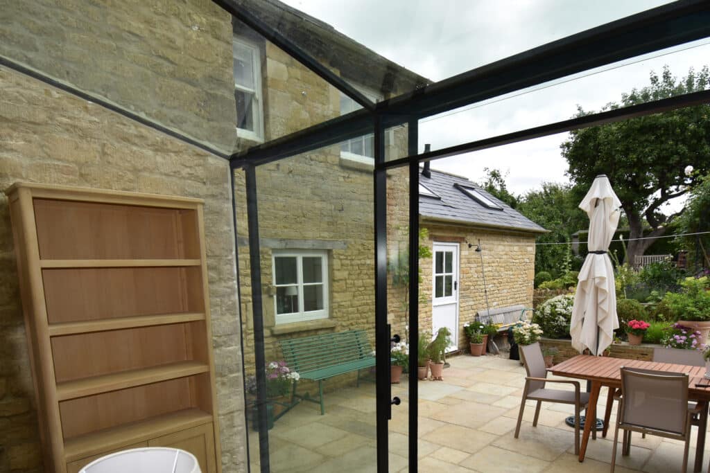 Internal junction showing glass roof and wall panes fitted flush into Cotswold stone wall.