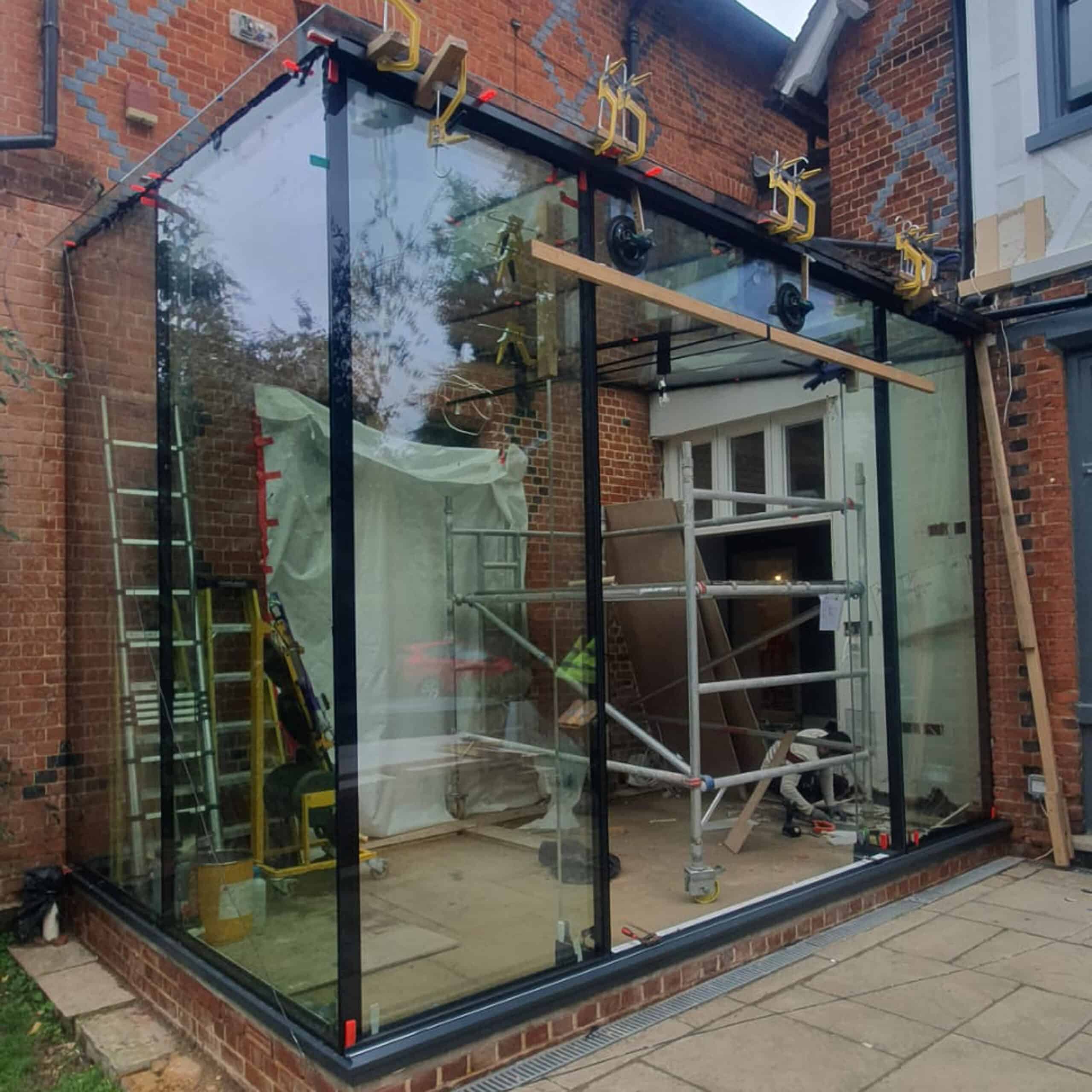 External view of the frameless glass extension being assembled on site.