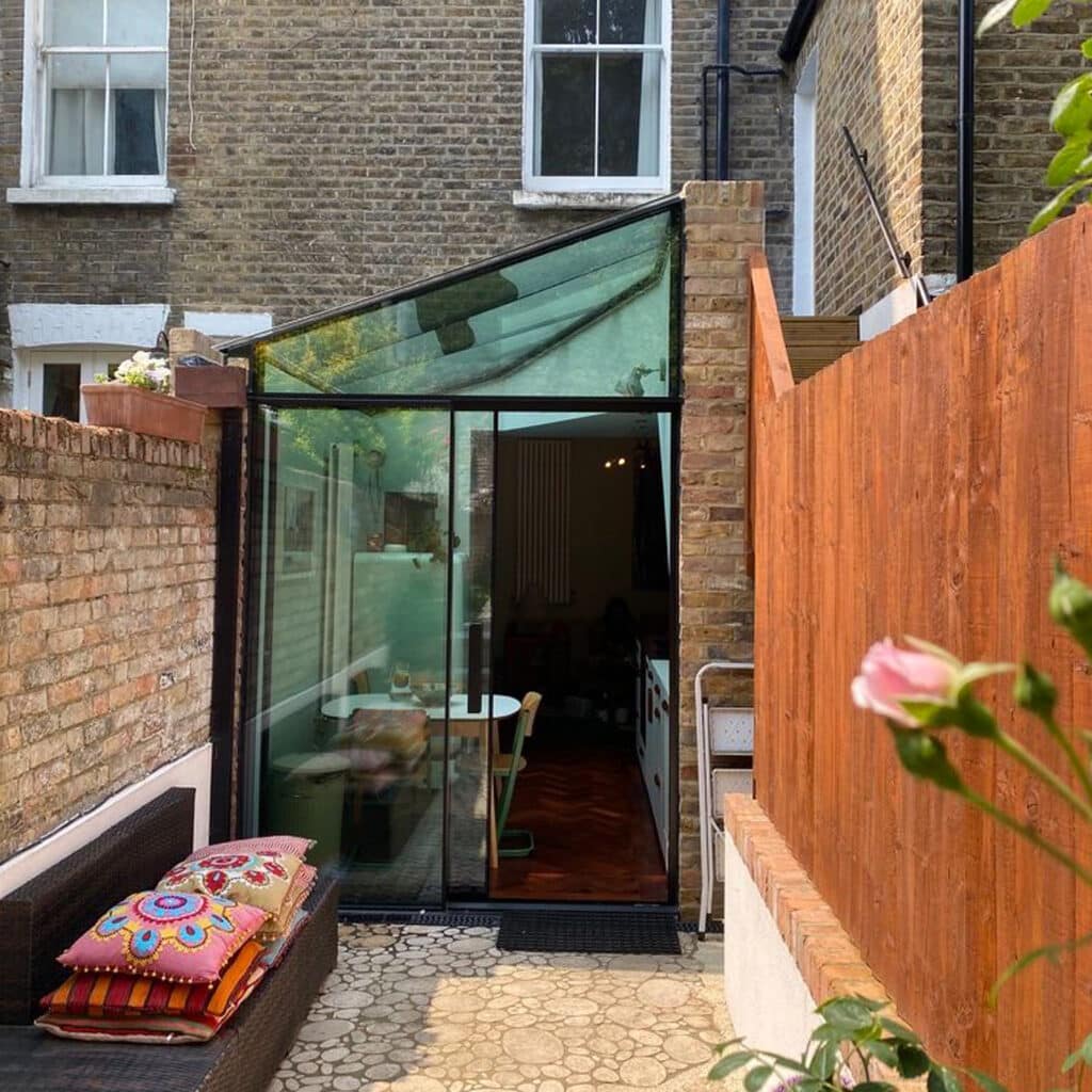 Exterior garden view of a small London glass extension with full-height glazing.