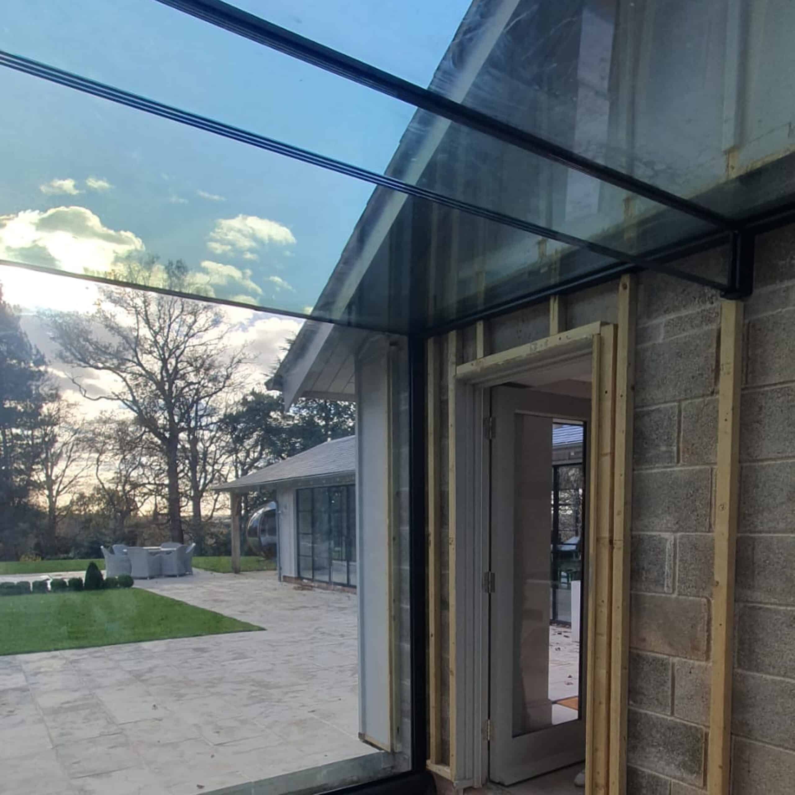 Glass elevation and roof of the link under construction, supported by a clear triple laminated low iron glass beam against the annexe