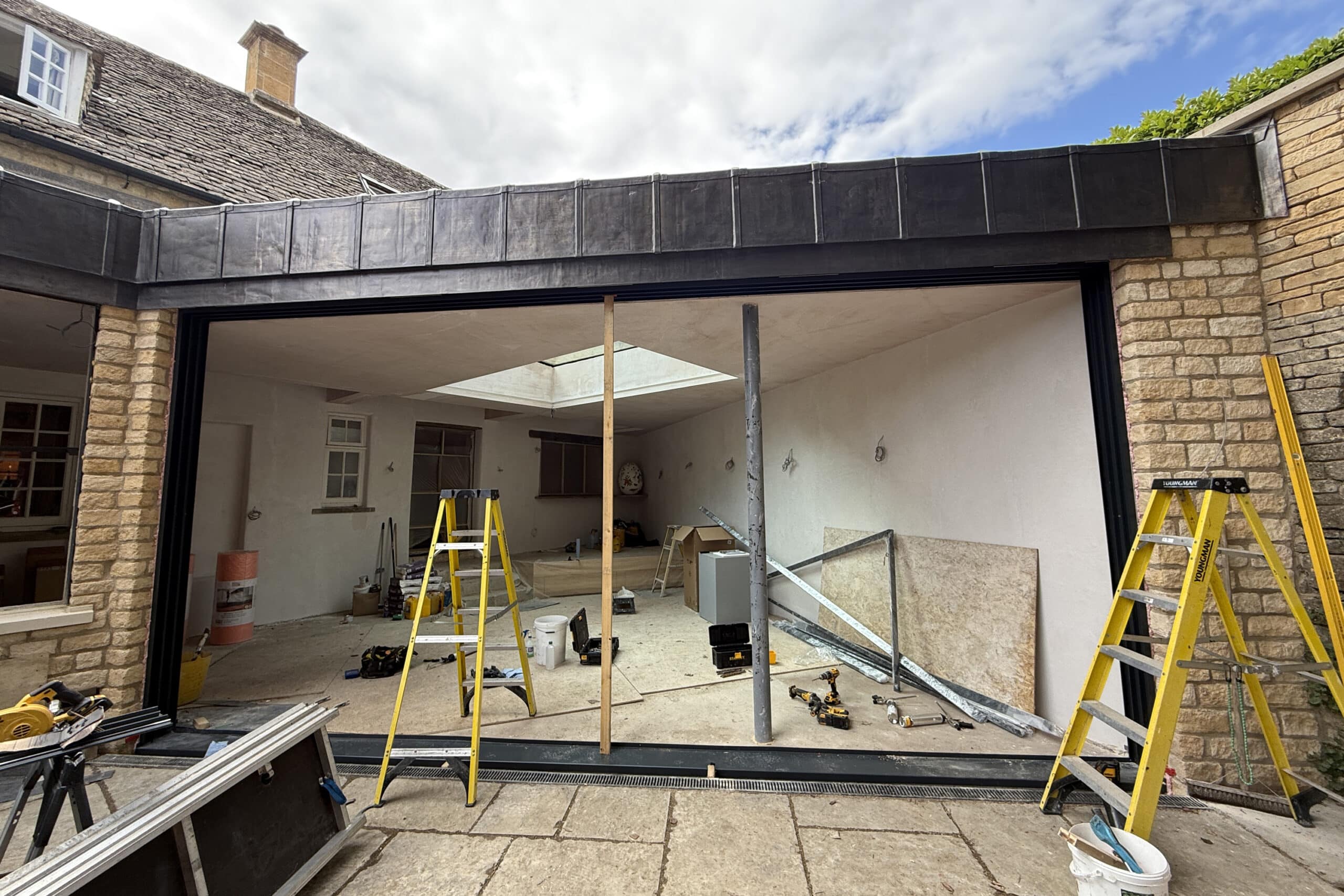 Head track, jambs, and base pressing installed to prepare for three-panel frameless sliding door system